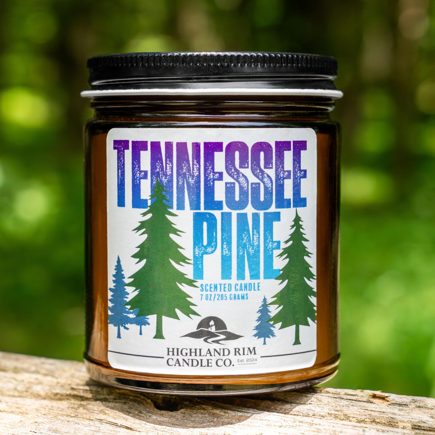 Tennessee Pine candle by Highland Rim Candle Co. placed on a log in a natural forest setting, echoing the fragrance of Tennessee pine woods.